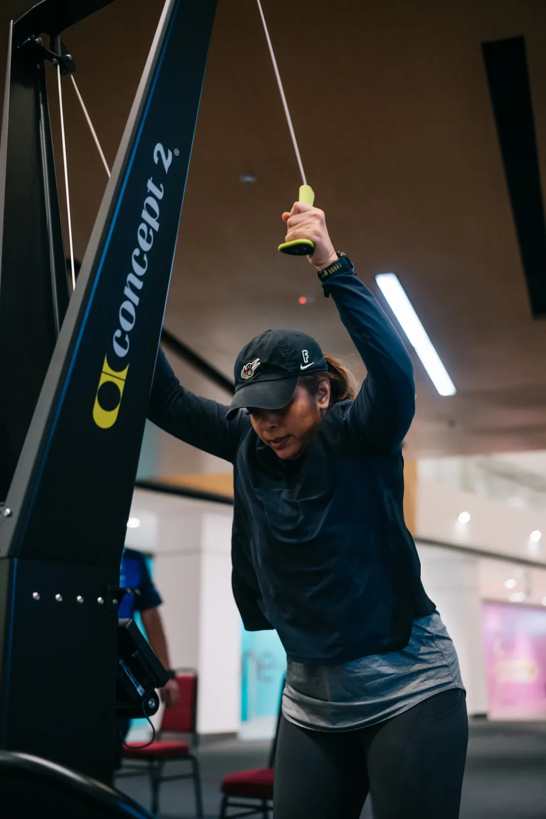 An athlete in a cap pulling the SkiErg overhead