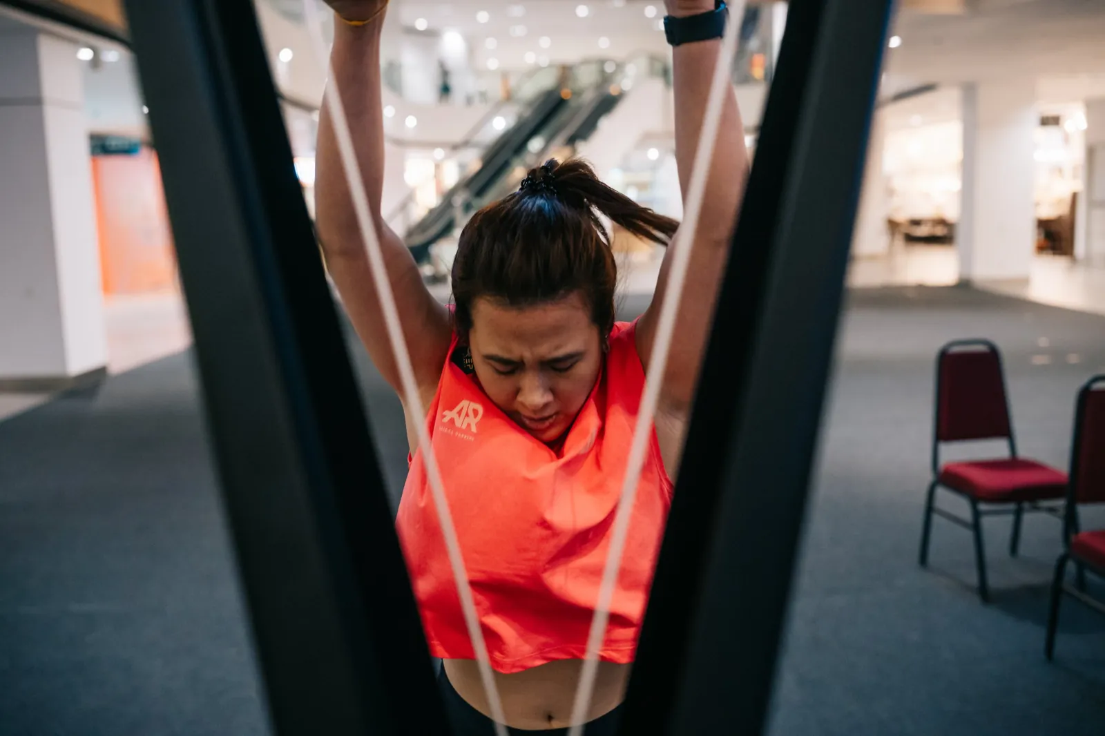 An athlete in coral shot through the SkiErg frame