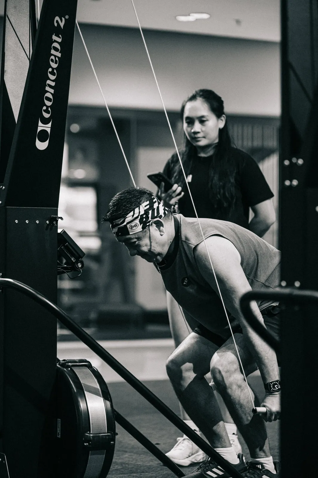 Black and white: an athlete on the SkiErg, a coach timing