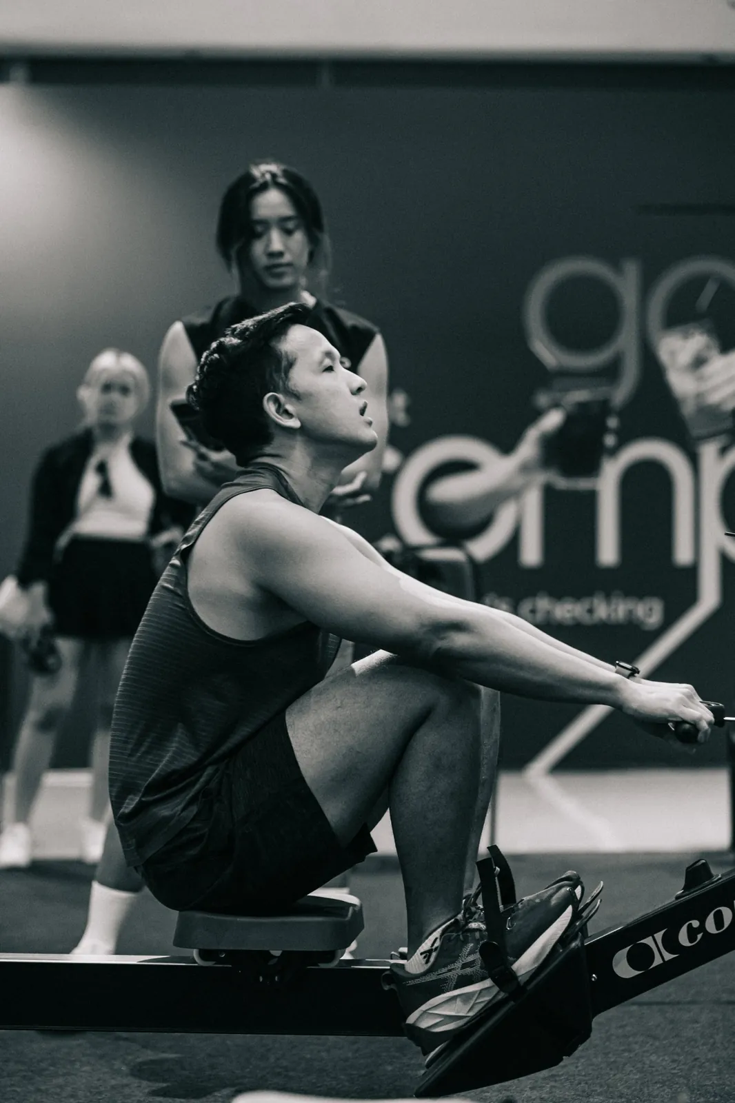 Black and white: a rower at the catch, a coach behind