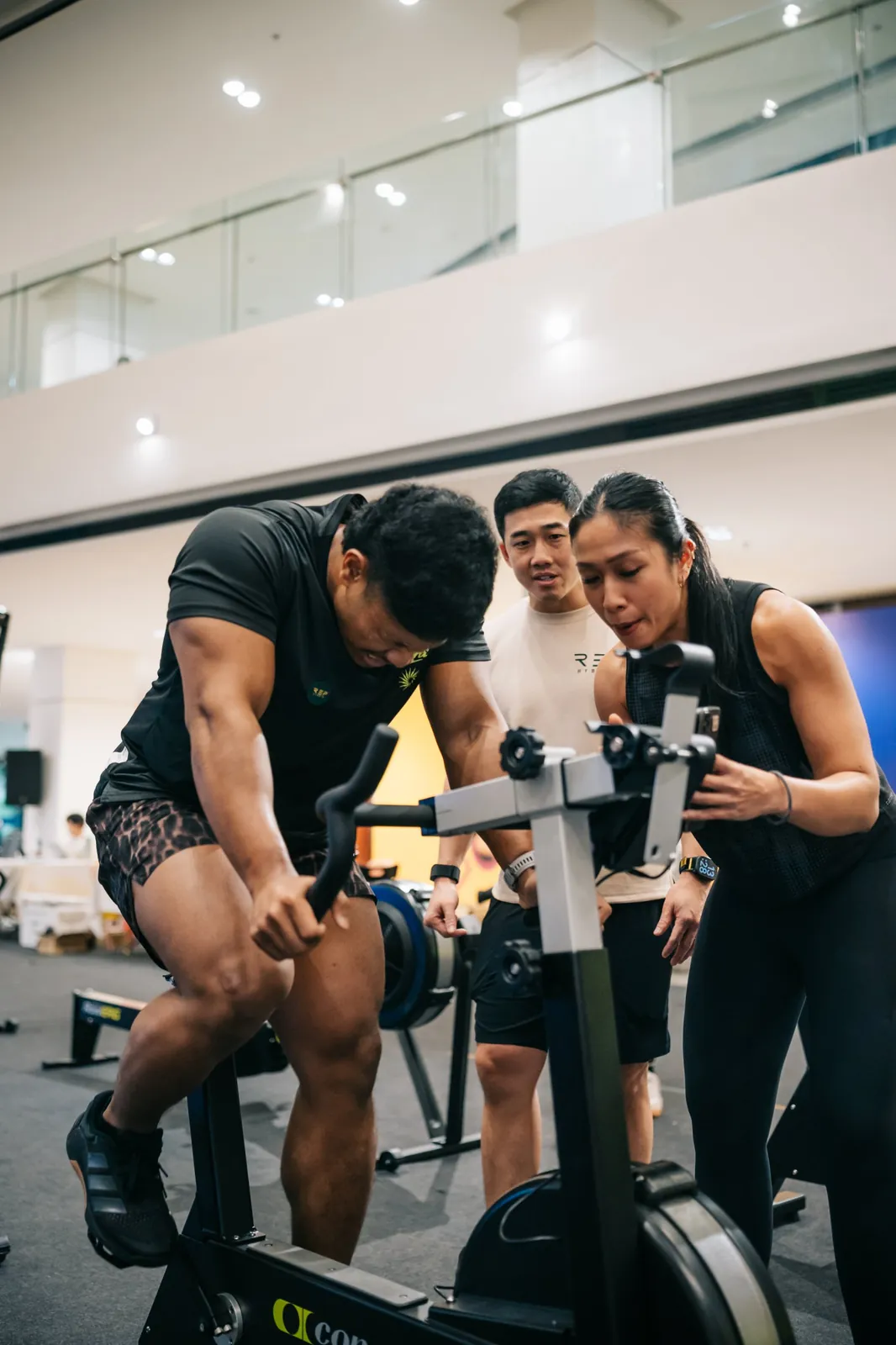 A coach leaning in over the bike to push an athlete on
