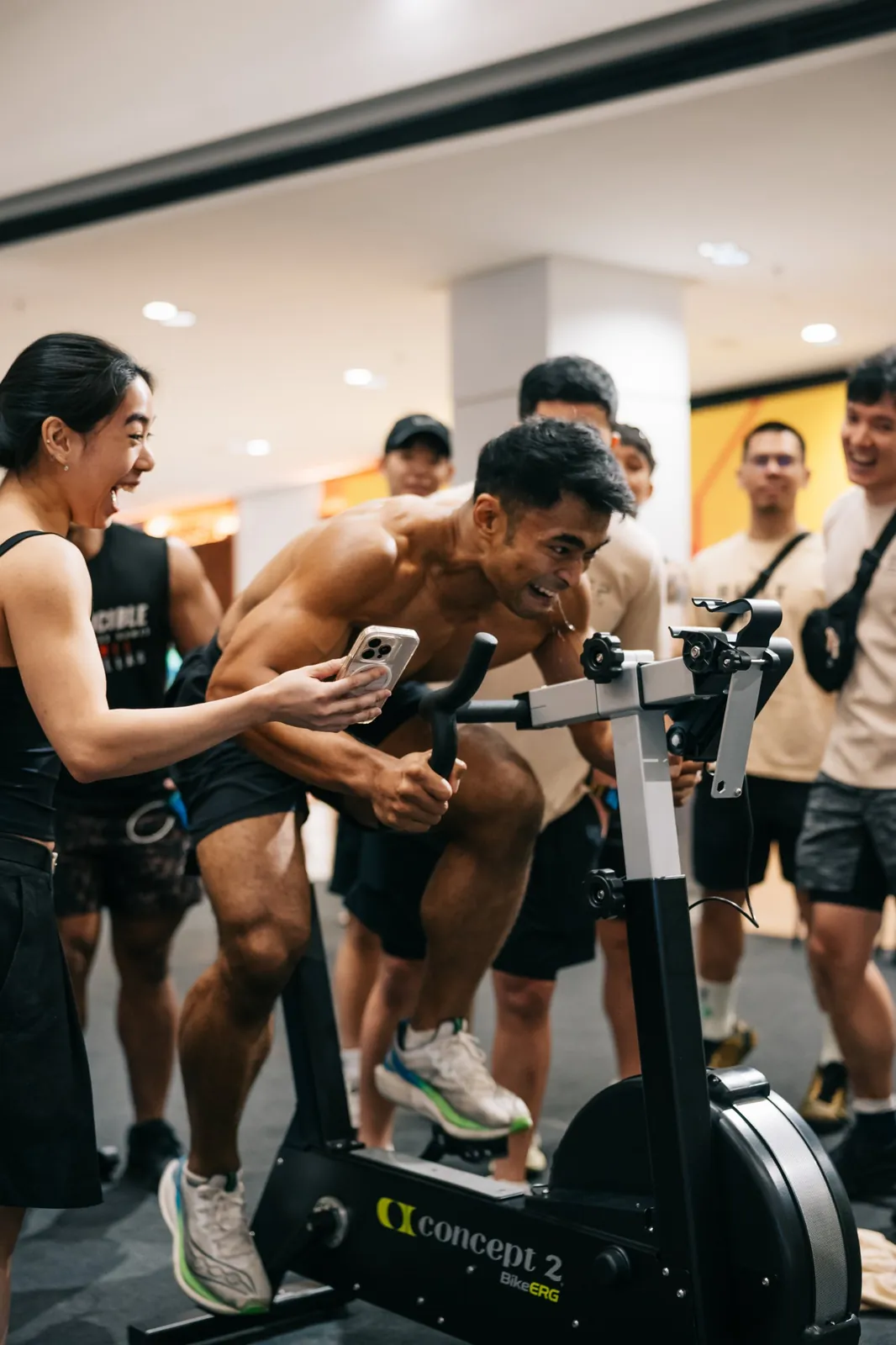 A shirtless athlete emptying the tank on the bike, crowd shouting