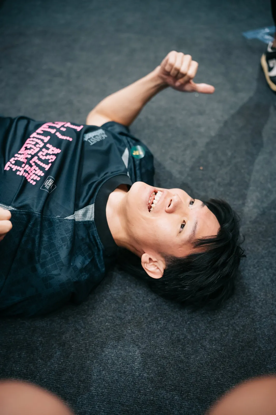 An athlete flat on the floor, thumbs up