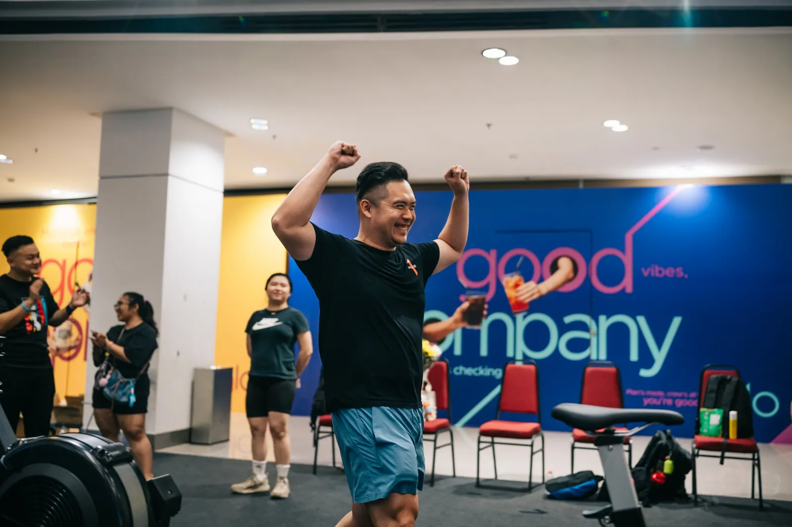 Arms up in front of the Good Company wall