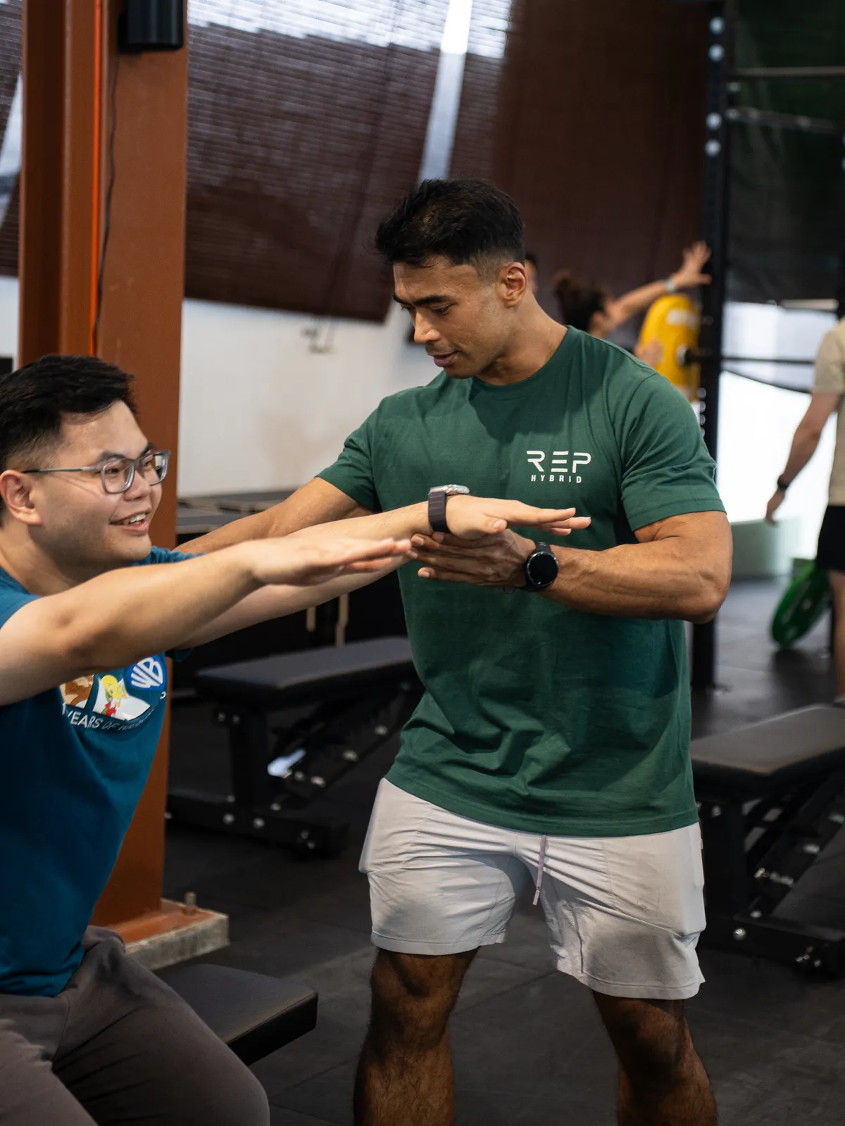 A coach in the green REP tee setting up a member's squat