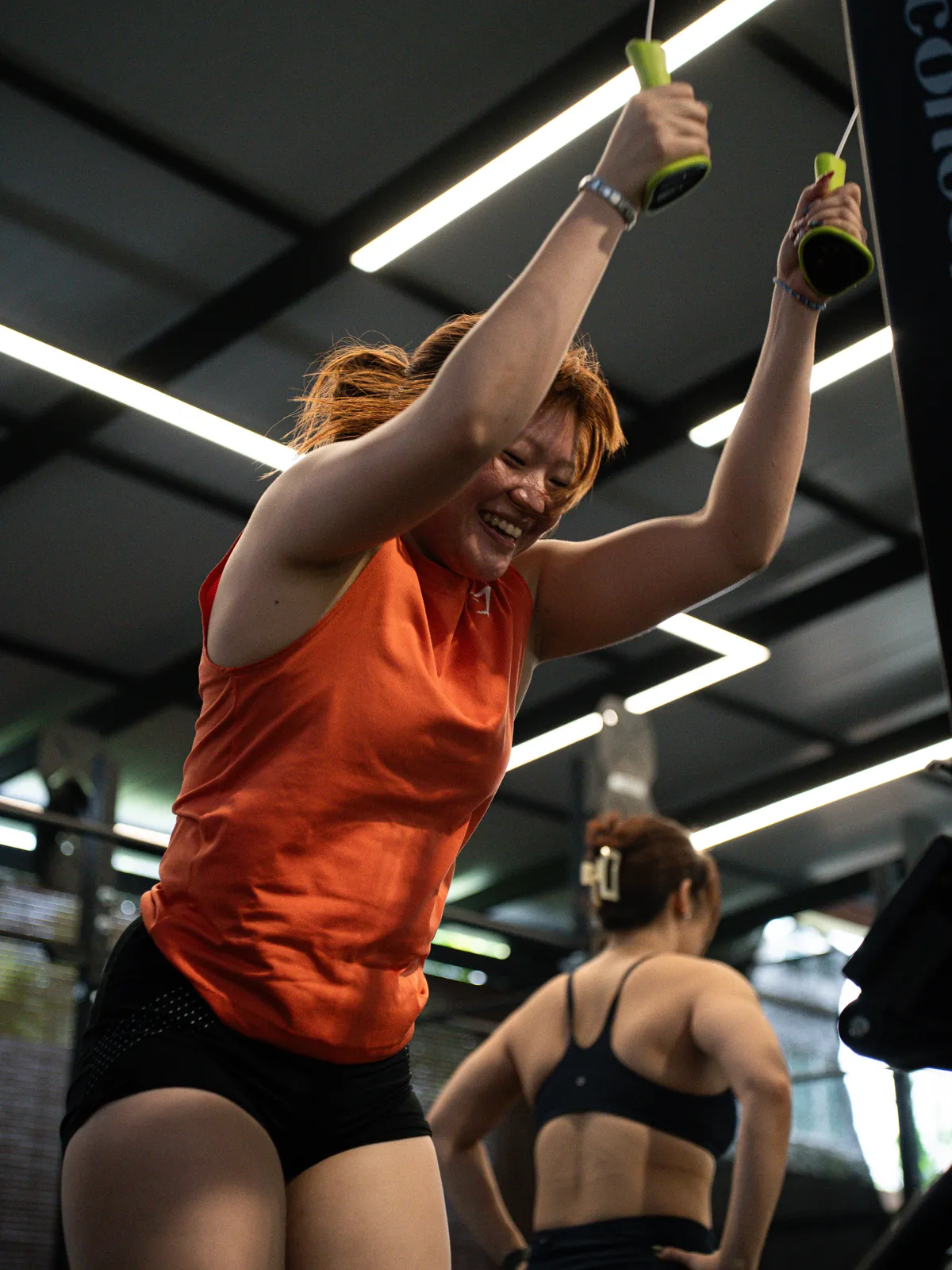 An athlete in orange grinning through a SkiErg pull