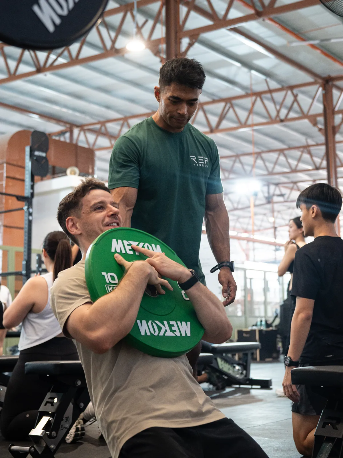 A coach standing over a member holding a plate to his chest