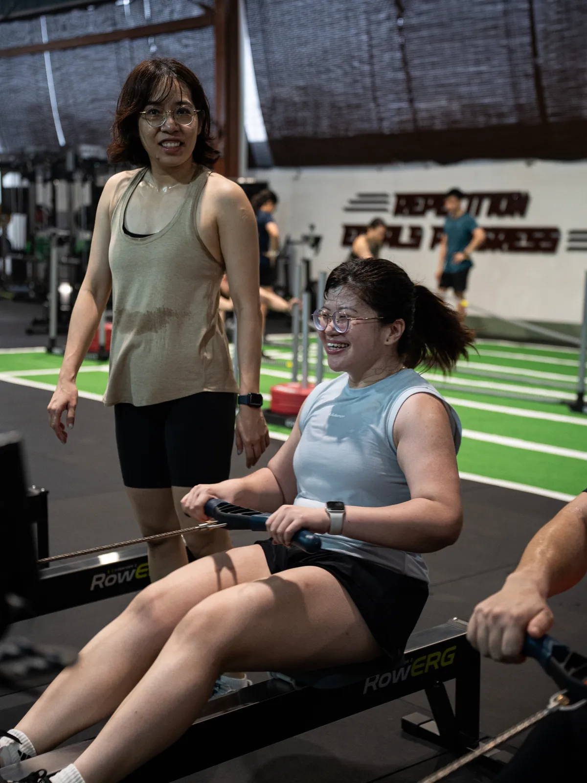A member smiling on the rower as her friend looks on