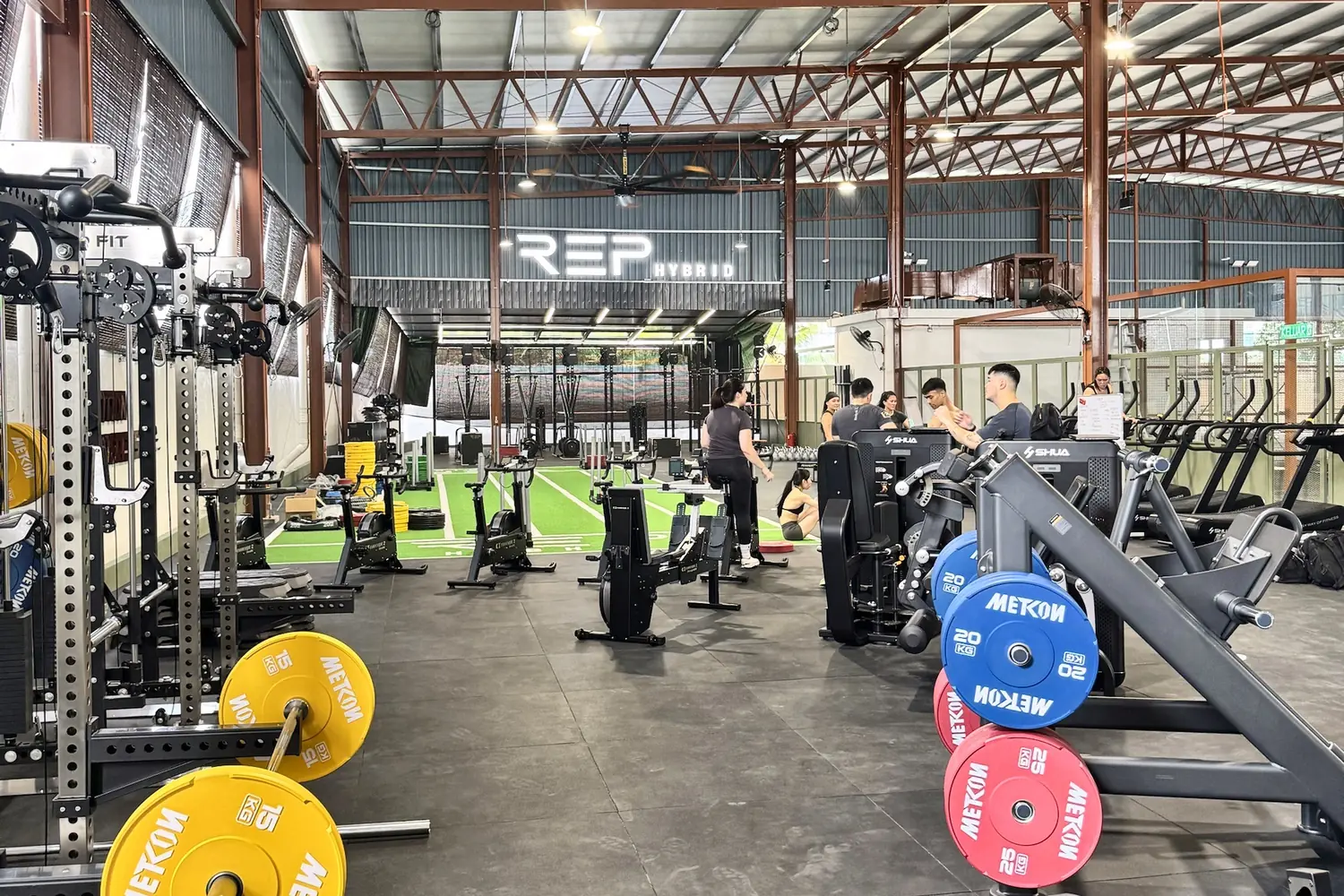 The main floor at REP HYBRID: loaded racks, SkiErgs and turf under the REP sign