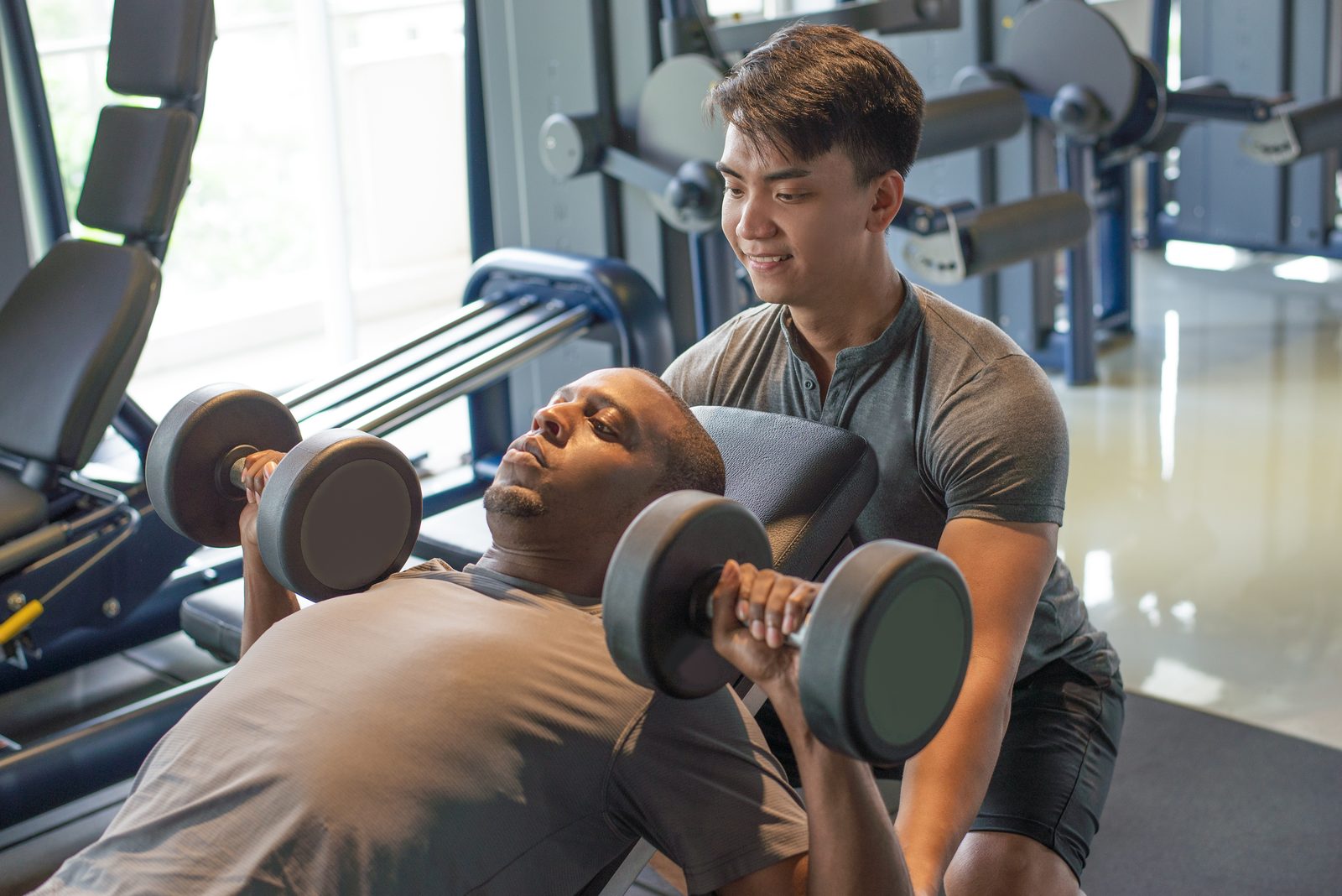 A coach setting the load on a dumbbell press
